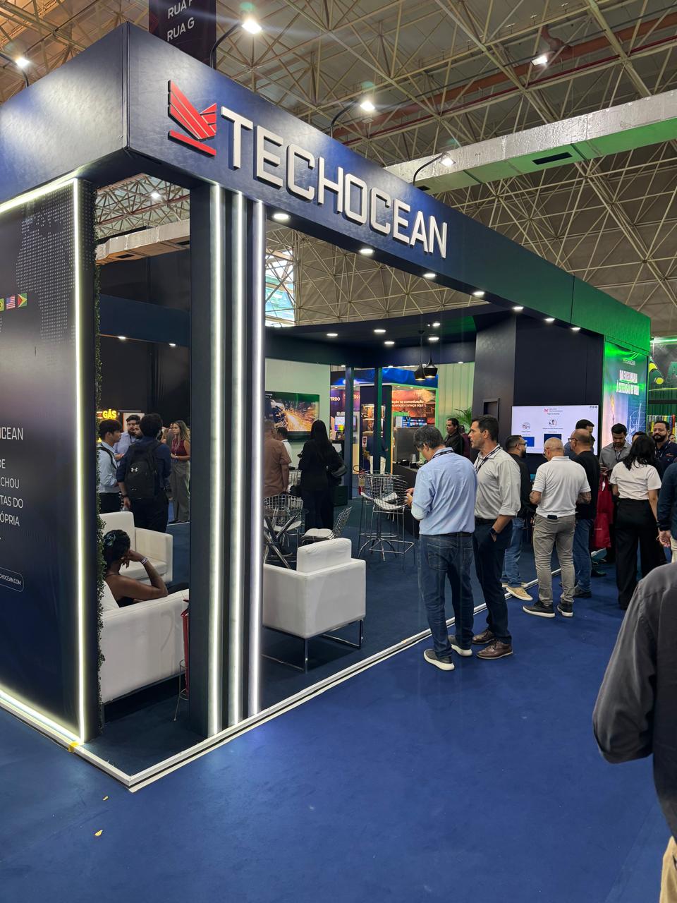 Stand TechOcean em evento, com público, iluminação e arquitetura de marca
